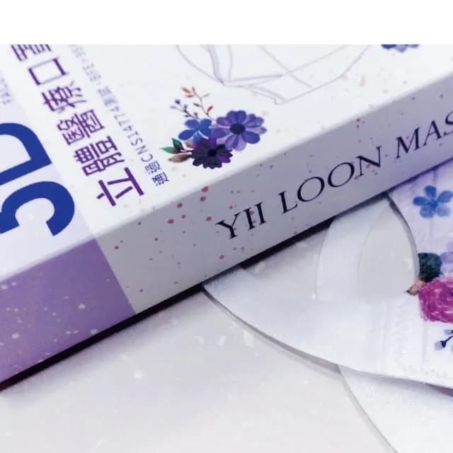 白色花卉圖案口罩盒近距離特寫，盒側清楚印有「YI LOON MASK」字樣，旁邊露出花朵口罩。