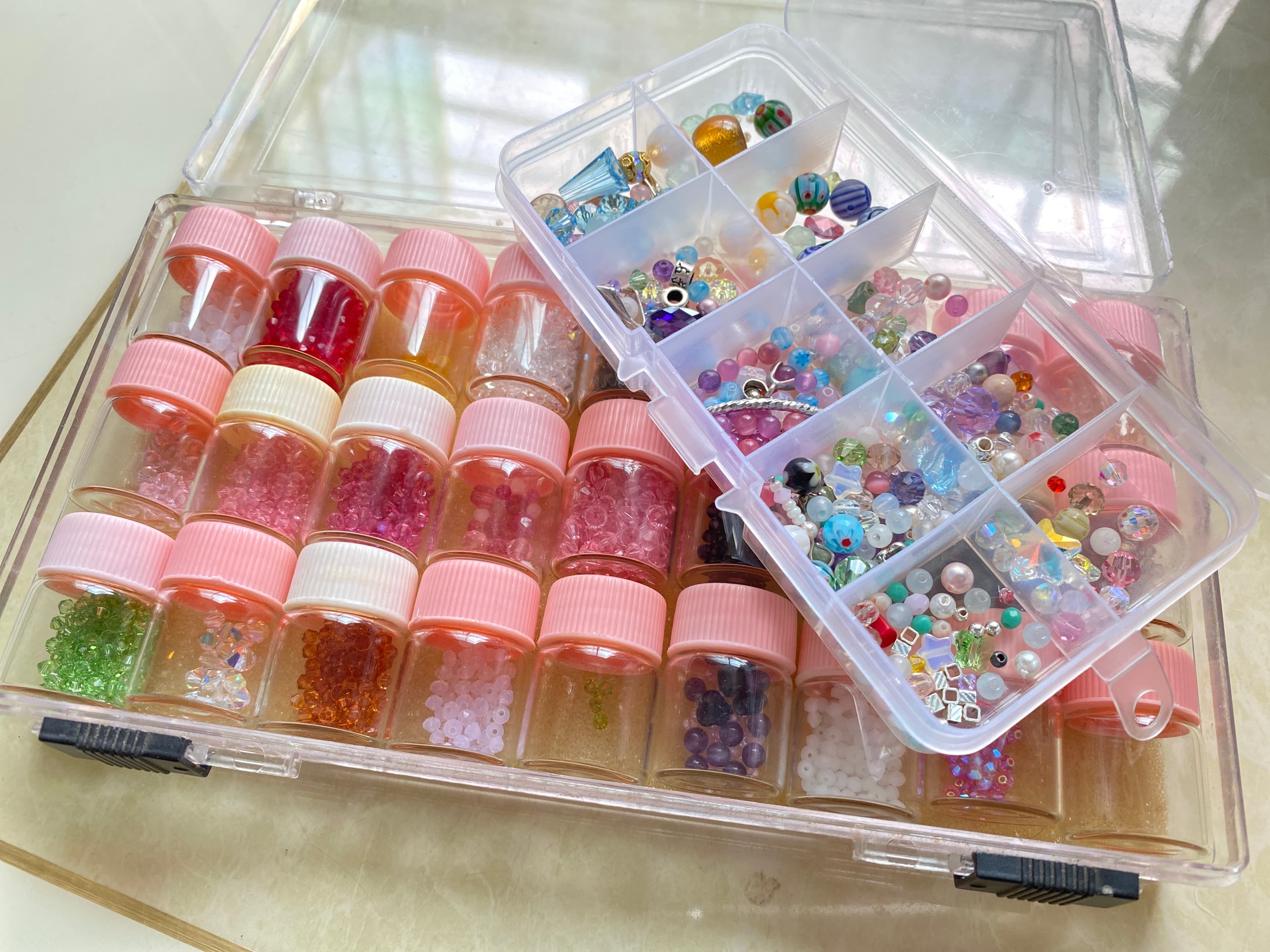 A transparent storage box filled with various colored beads, suitable for craft creation.