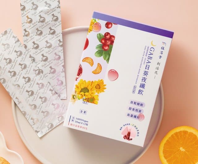 Packaging of Caihua Girl's GABA Night Fiber Drink, set against a simple light-colored plate with fruit elements.