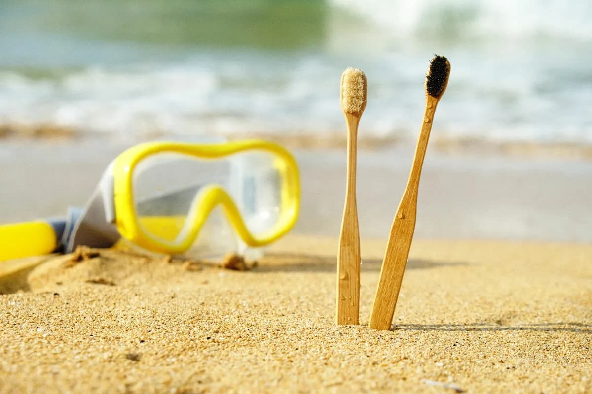 兩支Feelgood牙刷放在沙灘上,背景有潛水鏡和海浪,展現產品在生活情境中的使用。